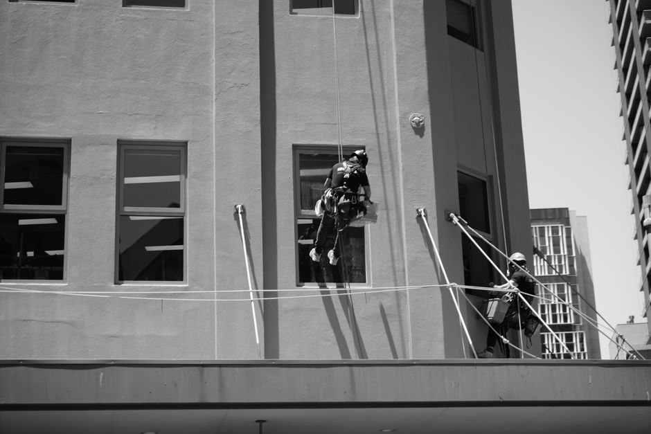 Window cleaners working on ropes outside a high-rise building, showcasing urban maintenance.